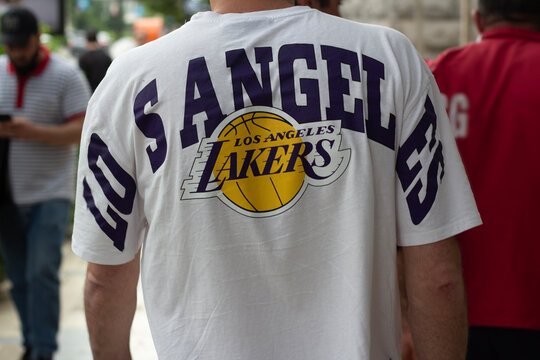 Tbilisi, Georgia - May, 27, 2024: Horizontal street photo close up. Back view. White man wearing white T-shirt with yellow and purple logo of Los Angeles Lakers basketball team. Concept of game, sport