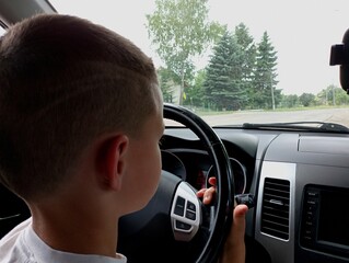 A minor boy driving a car. Driving a car. Topics of transport and underage drivers.