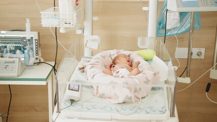 Two-day-old newborn baby in intensive care unit in a medical incubator. Newborn rescue concept. The work of resuscitation doctors. A newborn child in the hospital. Baby in vertex inside incubator.