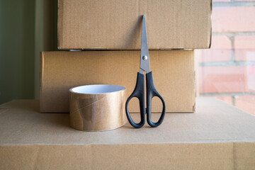 Cardboard box with duct tape and scissors on a window and room background, Online sales and packing...