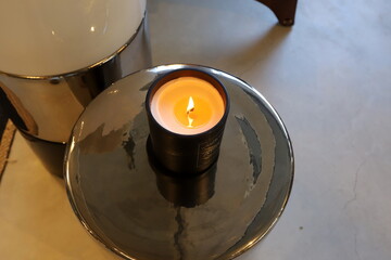 A burning wax candle stands on the table.