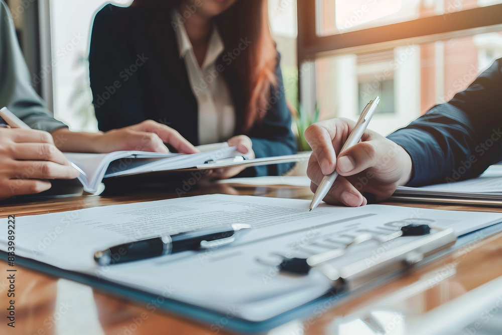 Wall mural business meeting with professionals discussing documents and writing notes at a desk in an office se