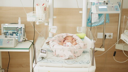 Two-day-old newborn baby in intensive care unit in a medical incubator. Newborn rescue concept. The work of resuscitation doctors. A newborn child in the hospital. Baby in vertex inside incubator.