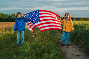 Little boys - American patriots kids with national flag on countryside road.