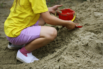 The child plays with sand and plastic toys.