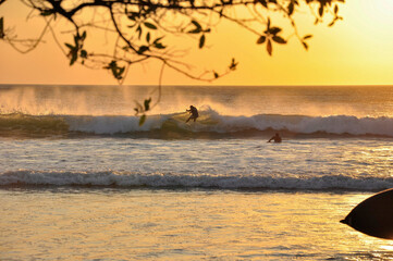 Persona practicando surf en una playa de Costa Rica en la puesta de sol. 