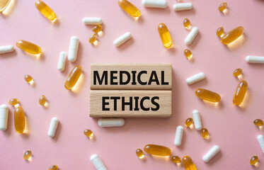 Medical Ethics symbol. Concept word Medical Ethics on wooden blocks. Beautiful pink background with...
