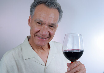 Mature Man smiling and holding up a big glass of red wine