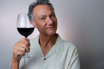 Mature Man smiling and holding up a big glass of red wine