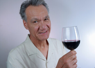 Mature Man smiling and holding up a big glass of red wine