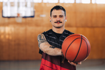 Handsome tattooed hispanic male basketball player with a ball in his hands