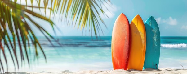 colored surfboards standing on a sandy beach against a serene blue ocean backdrop. copy space for text.