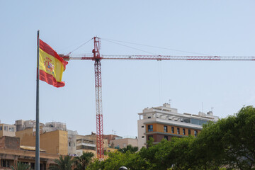 Economy and housing in Spain. Construction crane behind the flag of Spain