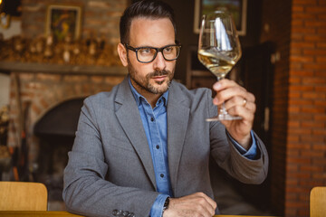 Adult man sit in a winery and hold glass of wine