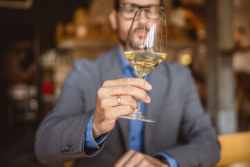 Adult man sit in a winery and hold glass of wine