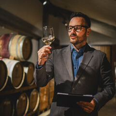 Adult winemaker stand between barrels check wine quality