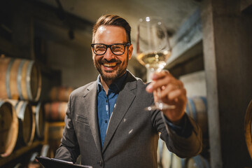 Portrait of man winemaker stand and hold glass of wine and clipboard
