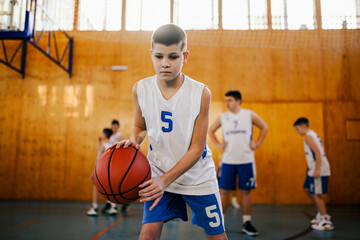 A focused junior basketball player dribbling a ball on his training.
