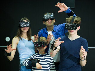 Positive family with children playfully poses in virtual reality glasses