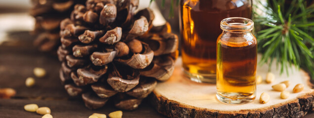 Organic essential oil, pine nuts, cedar cone on rustic wooden dark background. Concept of natural ingredients, naturopathy, herbal extracts and essence. Alternative medicine, aromatherapy banner