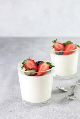 Panna cotta in glass with fresh berries - strawberries and blueberries on a gray background. Copy space. Italian dessert