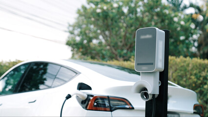 EV electric car recharge battery at parking lot in natural green city park. Alternative clean...