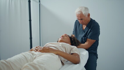 Clinic osteopath massaging woman pressing head zoom on. Focused man examine