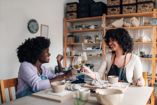 Diverse pottery course attendees making a toast with wine at workshop.
