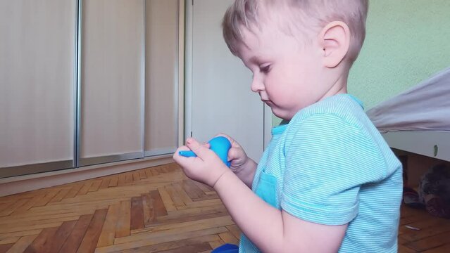 A charming boy is twirling an enema in his hands. Concepts of study, profession, medicine, training, role-playing games, children's entertainment, skills, care, toys, emotions, interest, care, pain