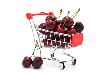 Shopping supermarket cart with fresh organic ripe cherries isolated on a white background. Purchase...