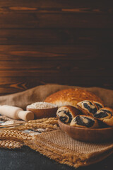 Naklejka premium Wooden board with tasty cut poppy seed bun on table