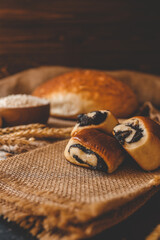 Fototapeta premium Wooden board with tasty cut poppy seed bun on table