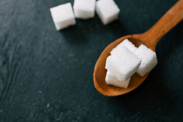 White crystalline sugar cubes on a wooden spoon