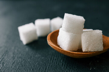 White crystalline sugar cubes on a wooden spoon