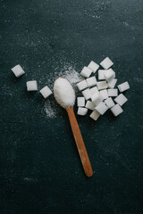 White crystalline sugar cubes on a wooden spoon