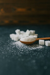 White crystalline sugar cubes on a wooden spoon