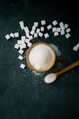 White crystalline sugar cubes on a wooden spoon