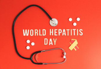 Stethoscope, pills tape and the inscription World Hepatitis Day on red.