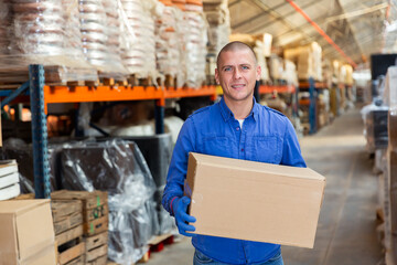 Positive warehouse worker dragging boxes on his hands