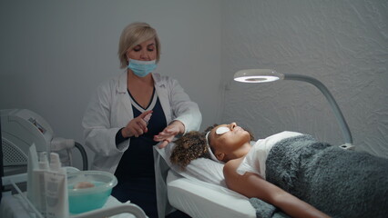 Doctor apply skin antiseptic in salon. Cosmetician spraying antibacterial liquid