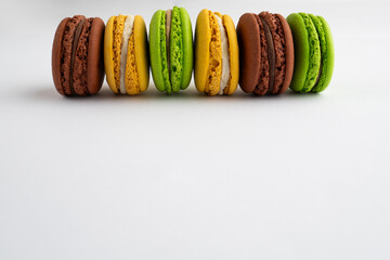 Colorful macarons are lined up on a white surface