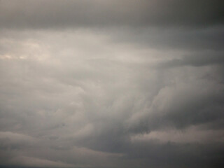 A cloudy sky with no sun. The sky is grey and the clouds are white. Nature background for design