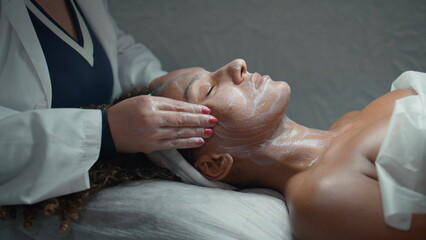 Beautician doing facial massage after peeling closeup. Hands touch patient skin
