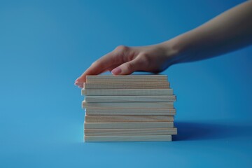 A person holding a stack of books on a blue surface