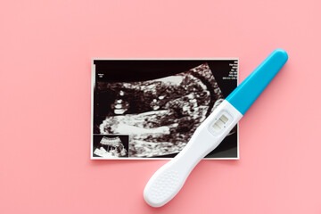 Positive pregnancy test. Photo of ultrasound and pregnancy test on a pastel pink background.