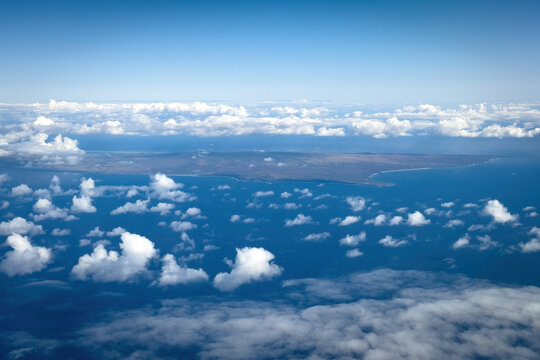 Aerial view of Hawaiian island of Molokai and its western coast against blue sky with clouds