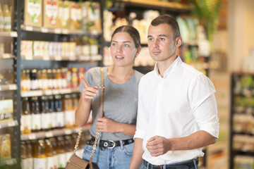 Positive friendly young adult couple, guy and girl, discussing organic and natural foods with...