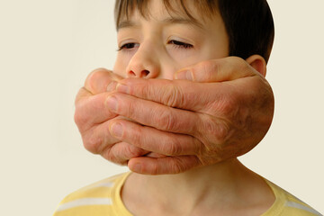 closeup rude male hands cover the mouth of a child, a boy suffers from violence, concept of...