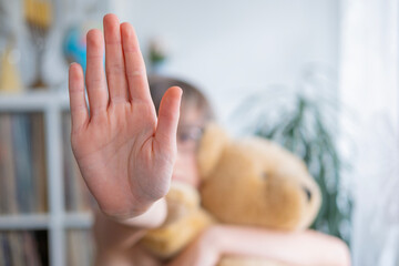 child with toy teddy bear, 11-year-old boy with defensive hand gesture, early diagnosis and...