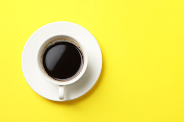 Cup of aromatic coffee on yellow background, top view. Space for text